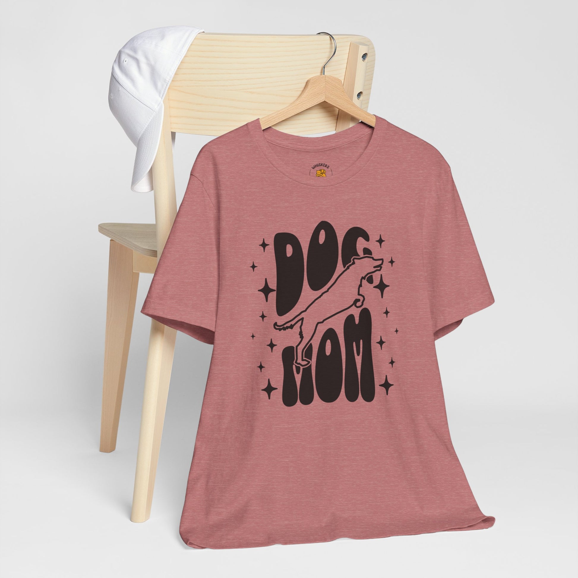 Pink t-shirt with 'Dog Mom' graphic on a wooden chair against a white background