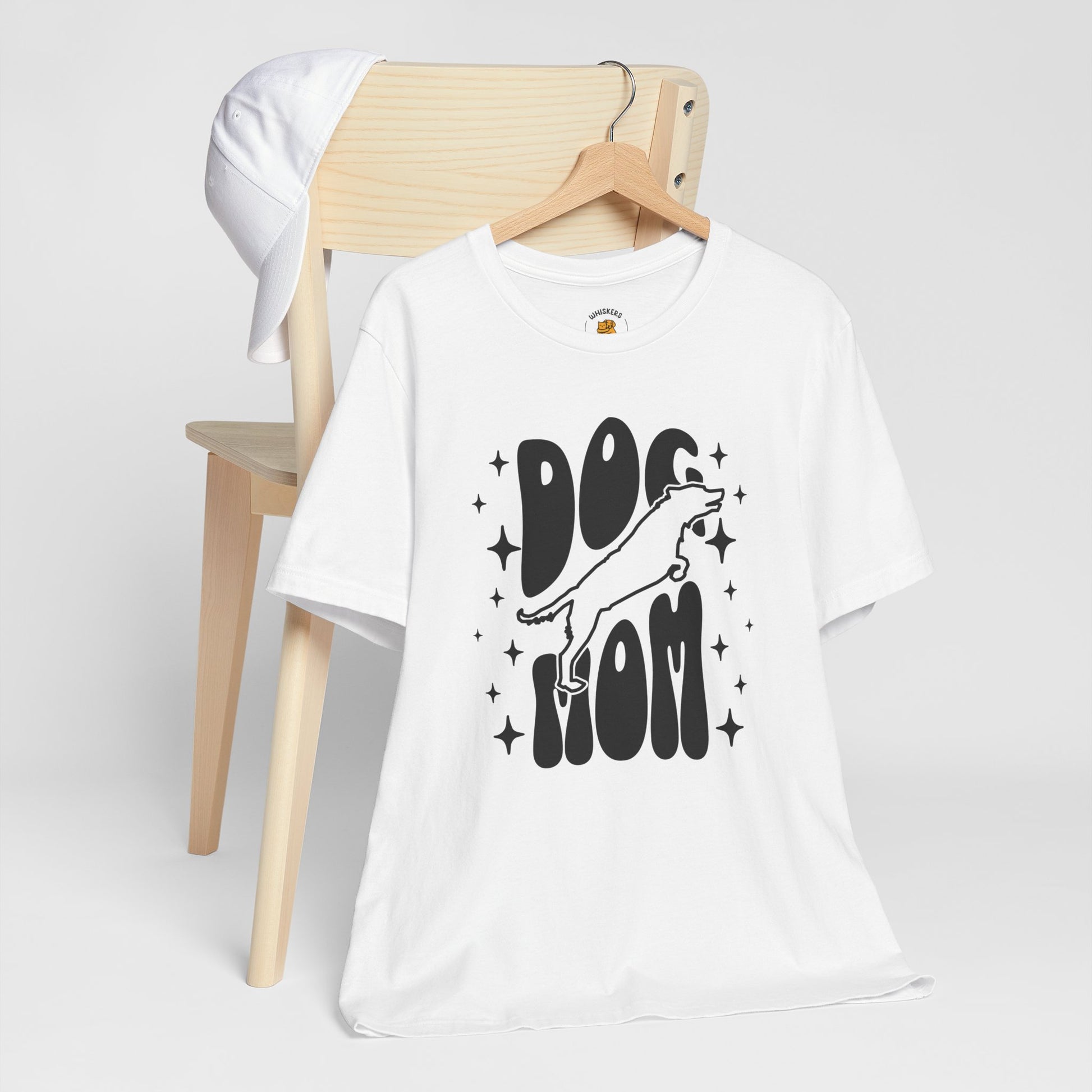 White t-shirt with 'Dog Mom' graphic on a wooden chair against a white background