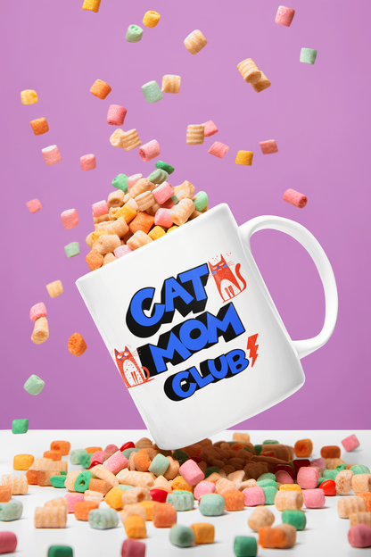 Cat Mom Club mug floating among cereal flakes — colorful retro ceramic mug with orange cat design
